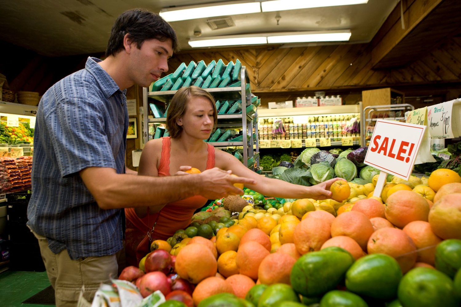 A couple (pre-COVID) picking out produce at a grocery store.